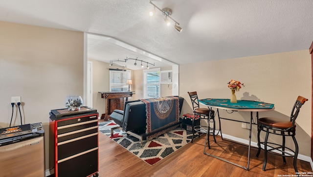 interior space featuring vaulted ceiling, a textured ceiling, hardwood / wood-style flooring, and rail lighting