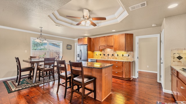 kitchen featuring stainless steel refrigerator with ice dispenser, a breakfast bar, dark wood-type flooring, and a kitchen island