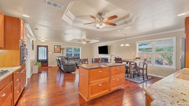 kitchen featuring crown molding, a healthy amount of sunlight, a kitchen island, and dark hardwood / wood-style floors