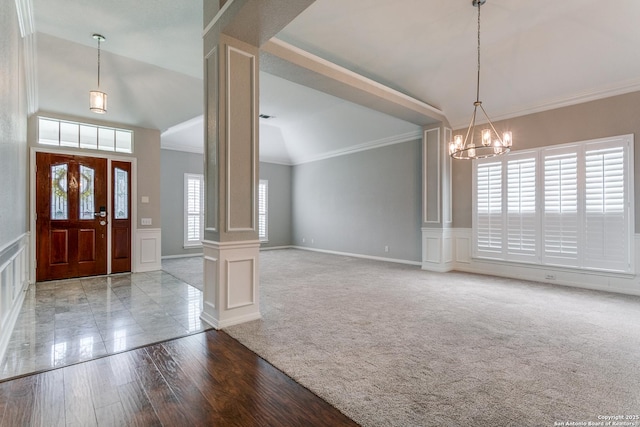 foyer entrance with a decorative wall, decorative columns, crown molding, a chandelier, and carpet