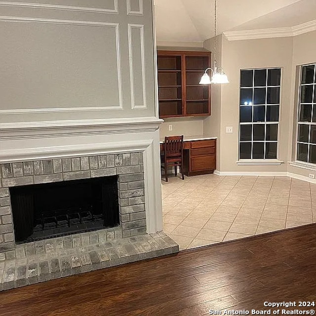 interior space featuring wood-type flooring, a brick fireplace, and ornamental molding