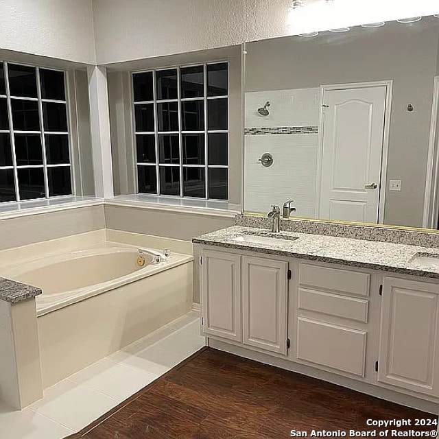 bathroom with independent shower and bath, vanity, and wood-type flooring