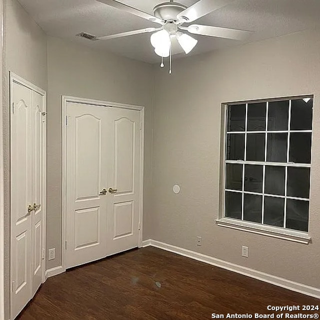 unfurnished bedroom featuring ceiling fan and dark hardwood / wood-style floors