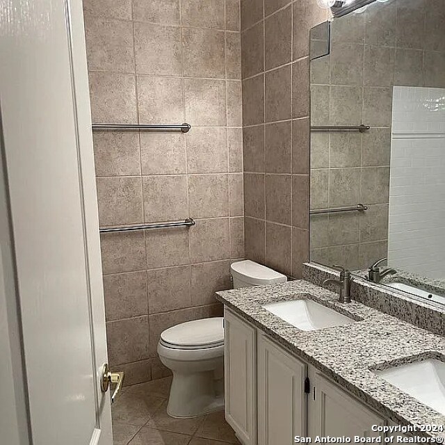 bathroom featuring tile walls, vanity, toilet, and tile patterned floors