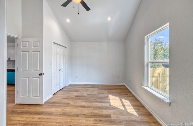 unfurnished bedroom with ceiling fan, a closet, light hardwood / wood-style floors, and high vaulted ceiling