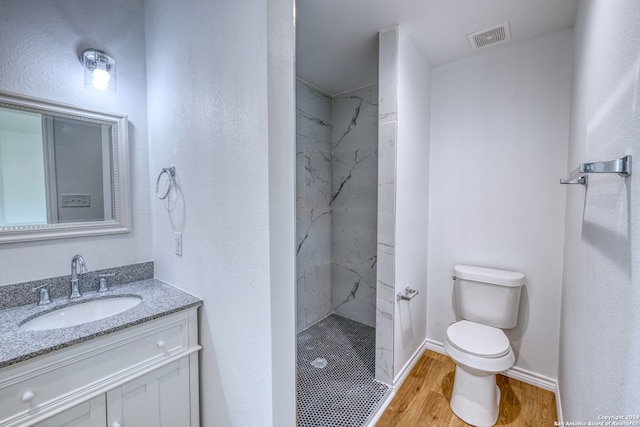 bathroom featuring vanity, toilet, hardwood / wood-style flooring, and tiled shower