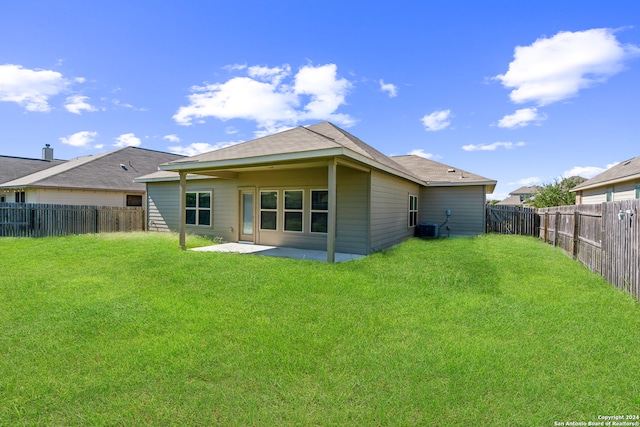 rear view of property featuring a patio, a yard, and central AC