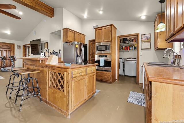 kitchen featuring appliances with stainless steel finishes, lofted ceiling with beams, washing machine and clothes dryer, hanging light fixtures, and a breakfast bar