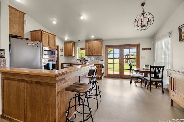 kitchen with decorative light fixtures, vaulted ceiling, a notable chandelier, french doors, and stainless steel appliances