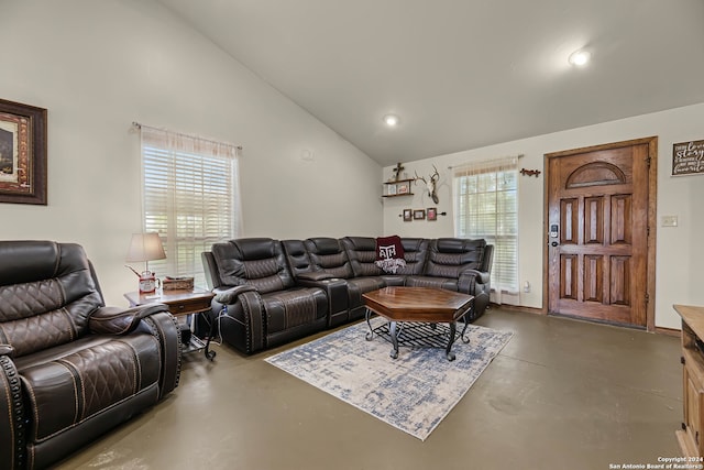 living room featuring concrete floors, vaulted ceiling, and plenty of natural light