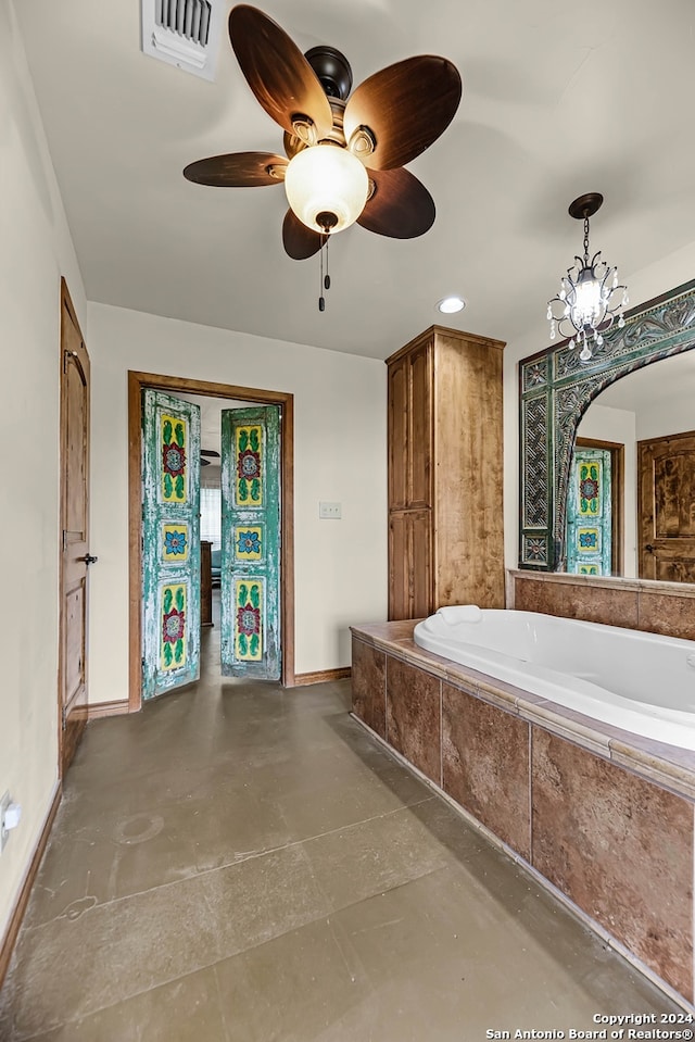 bathroom with a relaxing tiled tub, concrete flooring, and ceiling fan with notable chandelier