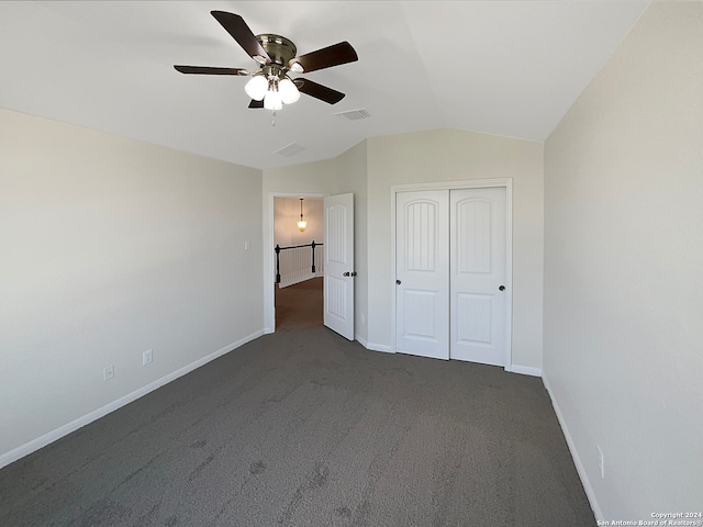 unfurnished bedroom with dark carpet, lofted ceiling, a closet, and ceiling fan