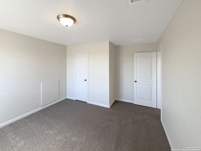 unfurnished bedroom with a closet and dark colored carpet