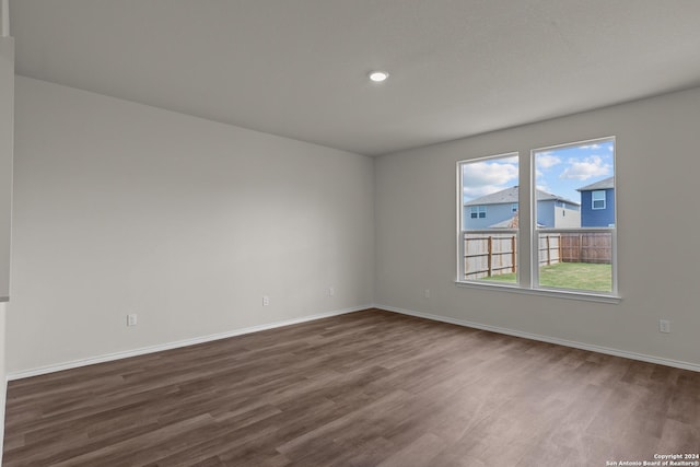 empty room featuring baseboards, dark wood-type flooring, and recessed lighting