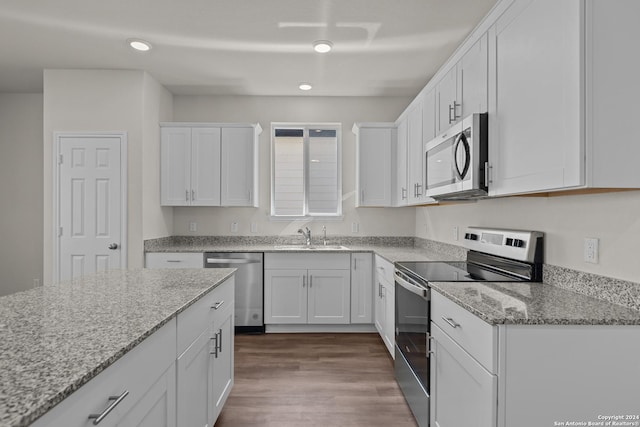 kitchen with dark wood finished floors, appliances with stainless steel finishes, white cabinetry, and a sink