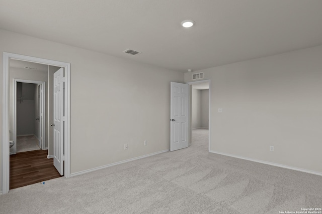 unfurnished bedroom featuring a walk in closet, carpet, visible vents, and baseboards
