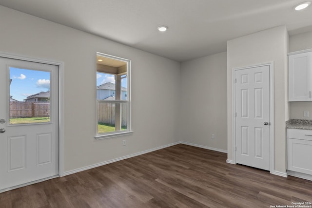 unfurnished dining area featuring recessed lighting, dark wood finished floors, and baseboards
