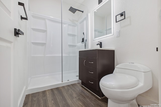 bathroom with wood-type flooring, vanity, walk in shower, and toilet