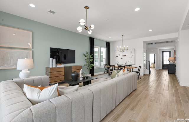 living room with light hardwood / wood-style flooring, a chandelier, and a healthy amount of sunlight