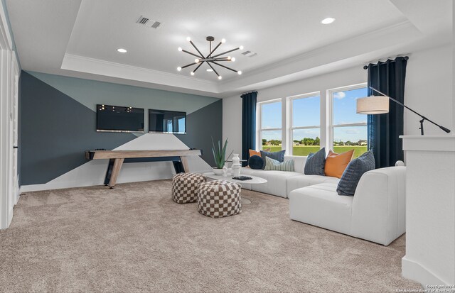 carpeted living room featuring ornamental molding, a tray ceiling, and a chandelier