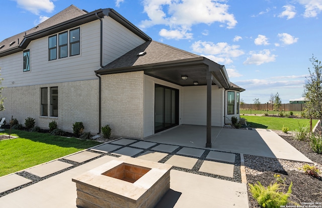 rear view of house with a patio area, an outdoor fire pit, and a yard