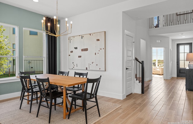 dining area featuring a notable chandelier, a towering ceiling, and light hardwood / wood-style floors