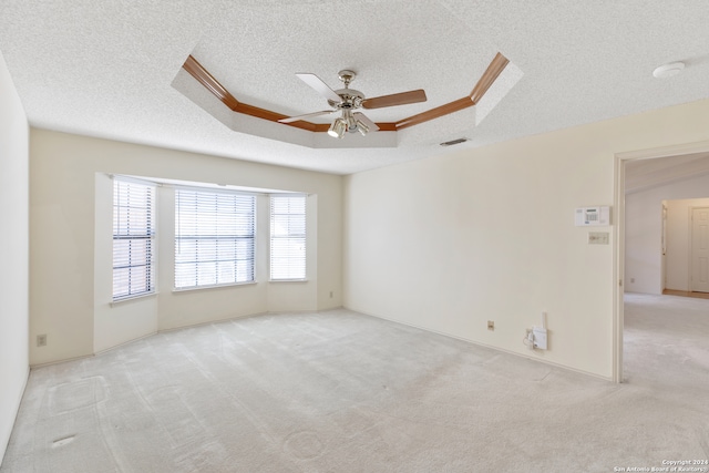 empty room with ceiling fan, a textured ceiling, and light carpet