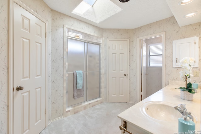 bathroom featuring vanity, a skylight, and a shower with door