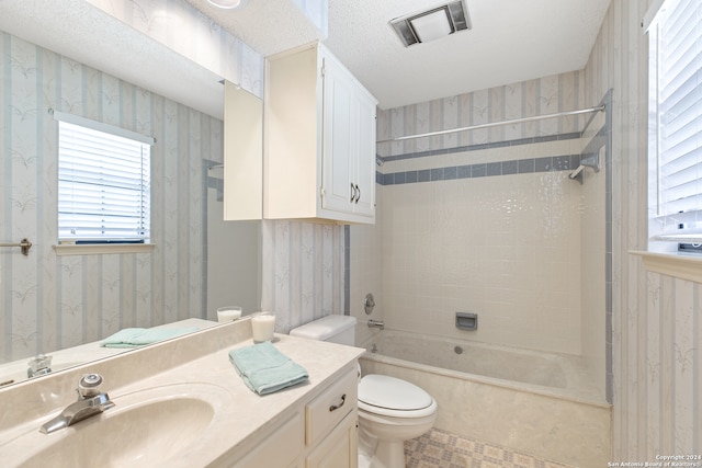 full bathroom featuring tile patterned flooring, a textured ceiling, tiled shower / bath combo, vanity, and toilet