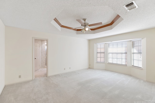 carpeted empty room with ceiling fan, a raised ceiling, and a textured ceiling