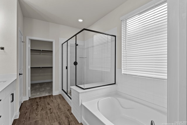 bathroom with wood-type flooring, vanity, shower with separate bathtub, and a wealth of natural light