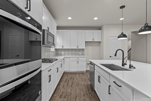 kitchen with white cabinets, appliances with stainless steel finishes, decorative light fixtures, and sink