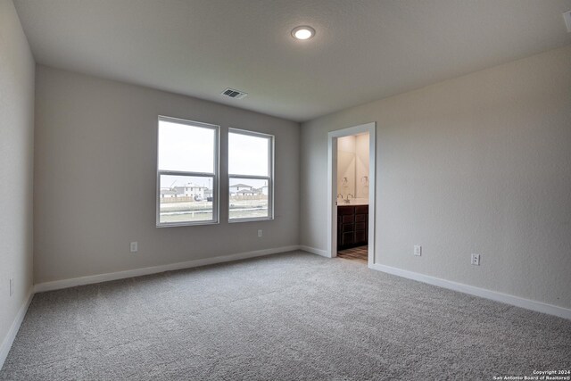 unfurnished bedroom featuring light colored carpet and ensuite bath