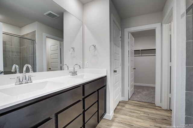 bathroom with wood-type flooring, vanity, and a tile shower