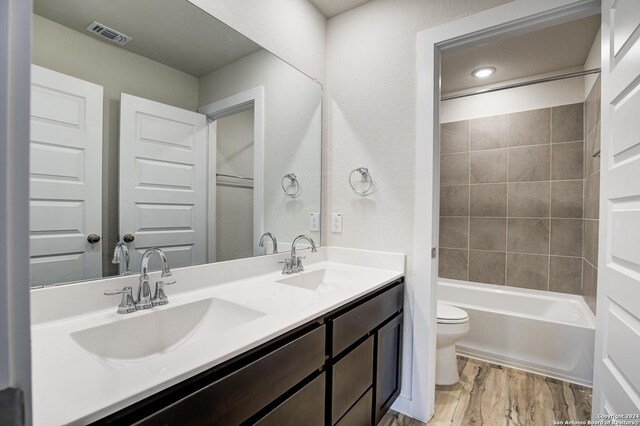 full bathroom with toilet, hardwood / wood-style floors, vanity, and tiled shower / bath