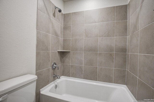 bathroom featuring toilet and tiled shower / bath