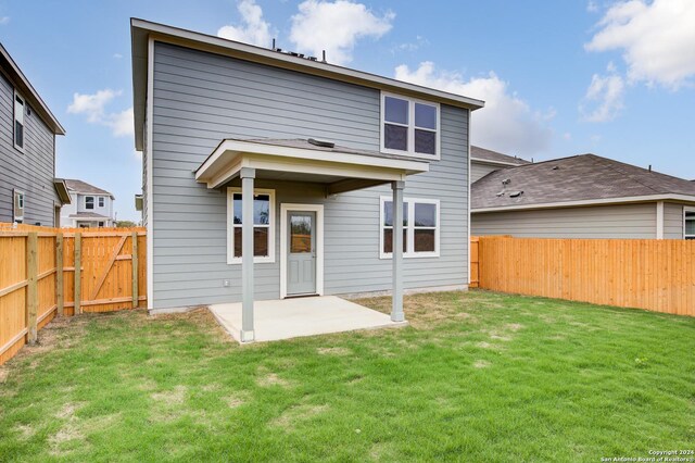 back of property with a lawn and a patio area