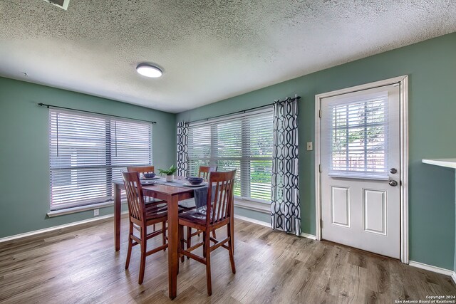 dining space featuring light hardwood / wood-style floors and a textured ceiling