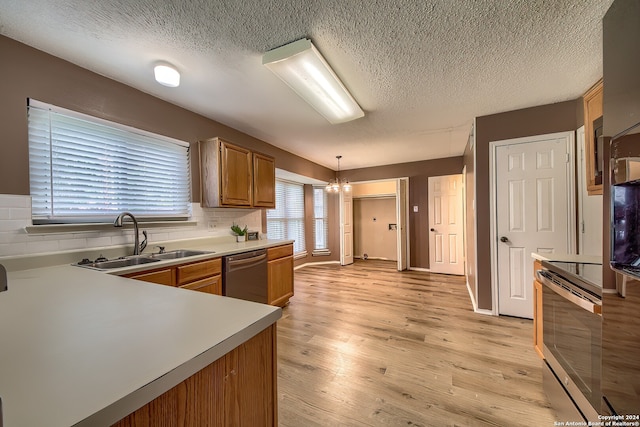 kitchen featuring tasteful backsplash, pendant lighting, stainless steel appliances, light hardwood / wood-style flooring, and sink