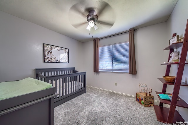 bedroom featuring ceiling fan, a nursery area, and carpet