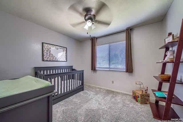 bedroom with a nursery area, carpet floors, ceiling fan, and baseboards