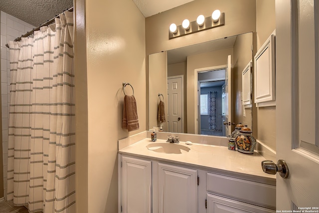 bathroom with a textured ceiling, walk in shower, and vanity