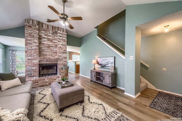 living room with ceiling fan, lofted ceiling, a fireplace, and light hardwood / wood-style flooring