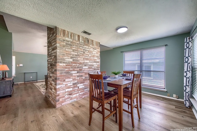 dining area with baseboards, wood finished floors, visible vents, and a textured ceiling