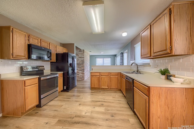 kitchen featuring a textured ceiling, black appliances, light hardwood / wood-style floors, and decorative backsplash