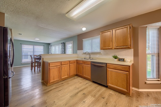 kitchen featuring appliances with stainless steel finishes, kitchen peninsula, light wood-type flooring, and sink