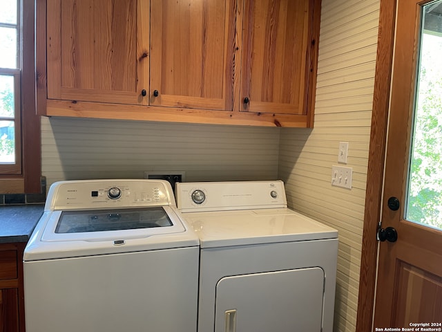 laundry room featuring cabinets, wood walls, and washer and dryer