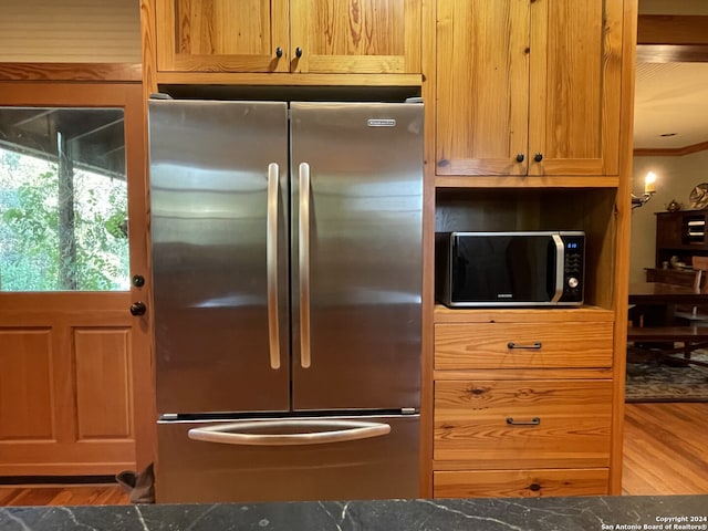 kitchen featuring ornamental molding, stainless steel appliances, hardwood / wood-style floors, and dark stone counters