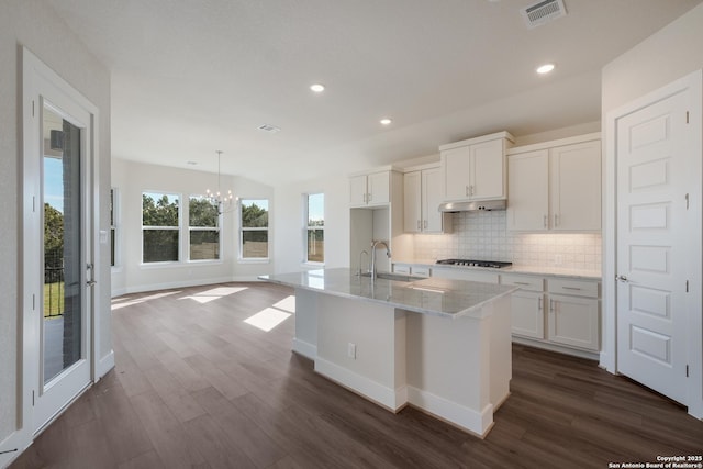 kitchen featuring an inviting chandelier, white cabinets, sink, decorative backsplash, and an island with sink