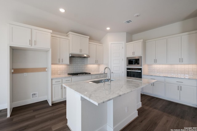 kitchen with built in microwave, sink, wall oven, a center island with sink, and white cabinets